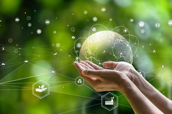 [Translate to English:] grüner Hintergrund, von rechts unten im Bild zwei Hände mit Unterarm, die durchsichtige Weltkugel halten