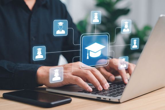 geöffneter Laptop mit darüber schwebenden Icons, davor Oberkörper einer Person sichtbar