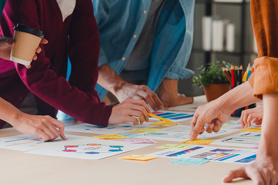 Menschen stehend bei Tisch und arbeiten an Zetteln