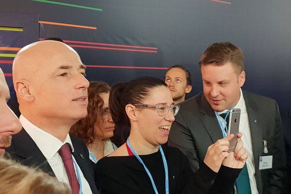 (from left to right) an exhibior, Julia Hofbauer laughing and taking a photo and Dr. Stefan Müller watching her smiling