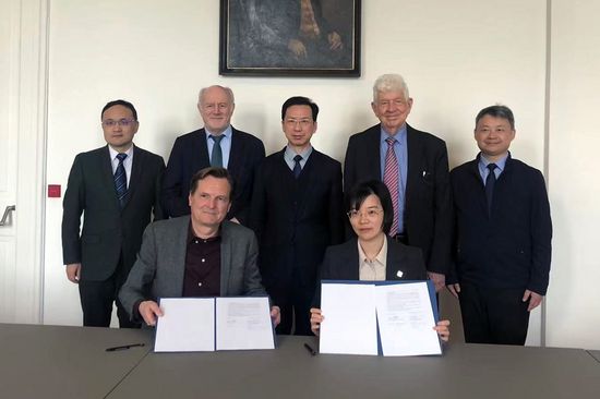 Gruppenfoto, zwei Personen halten unterzeichnete Papiere in den Händen