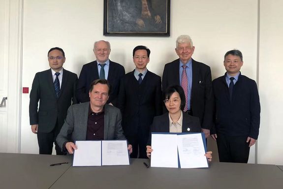 Gruppenfoto, zwei Personen halten unterzeichnete Papiere in den Händen