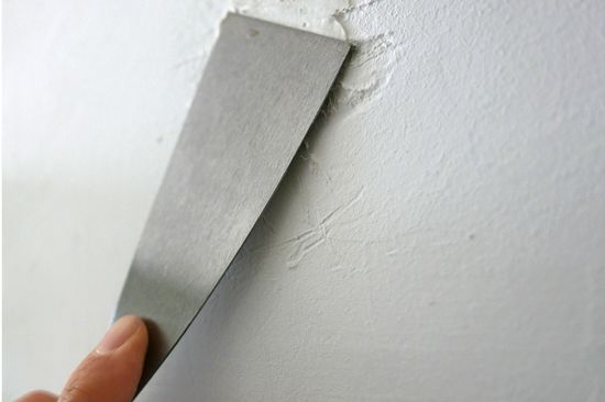  Photo filling an unevenness in the wall with a spatula. 
