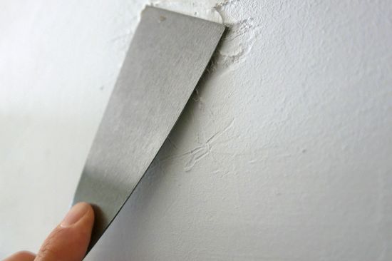 Photo filling an unevenness in the wall with a spatula. 