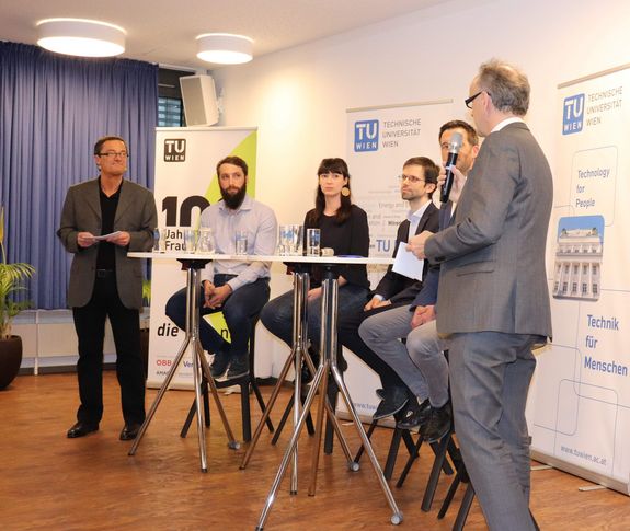 Opening of the 26th TU Forum Vice-Rector Fröhlich opens the TU Forum. Behind him is the podium on high chairs, to his left is the moderator. In the background TU Rollups can be seen.