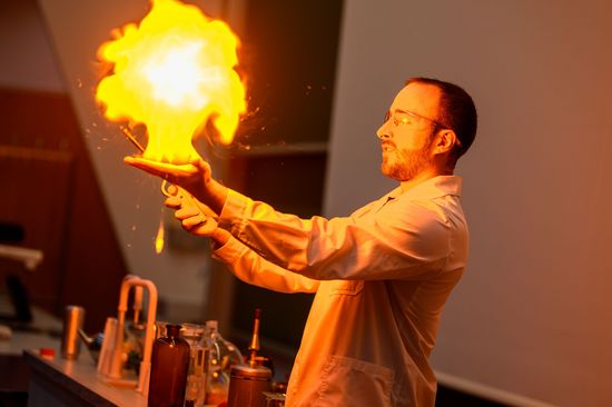 Alexander-Michael Prochazka im weißen Labormantel mit Feuer hantierend