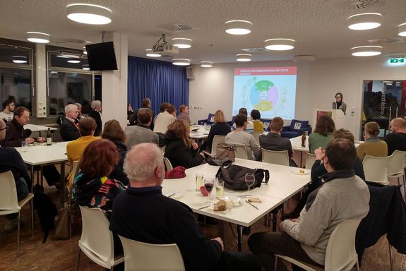 Sprecherin am Podium, Gäste sitzend