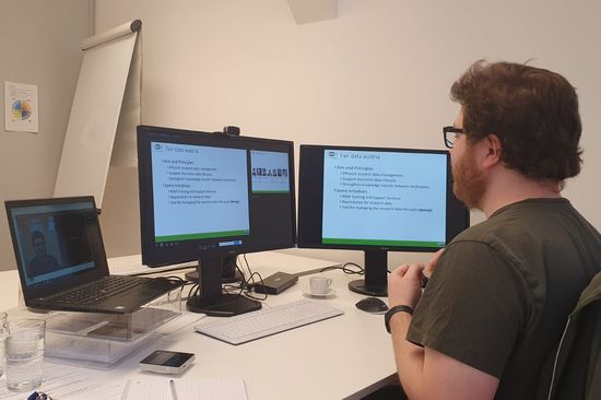 Foto von Zeno Casellato am Schreibtisch mit drei Bildschirmen während der Online-Präsentation