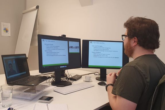 Photo of Zeno Casellato at his desk with three screens during the online presentation.