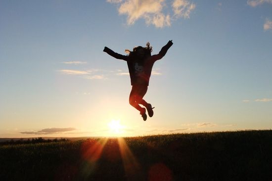 Frau springt vor Sonnenaufgang