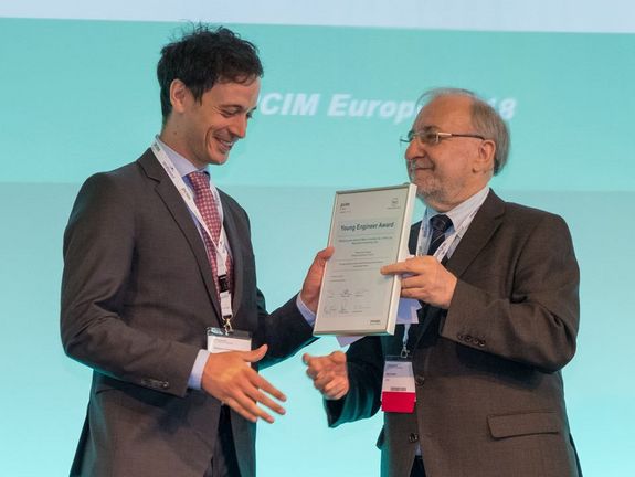 Freudige Preisübergabe mit Handeschütteln und Urkunde an Thomas Fuchslueger durch Prof. Leo Lorenz