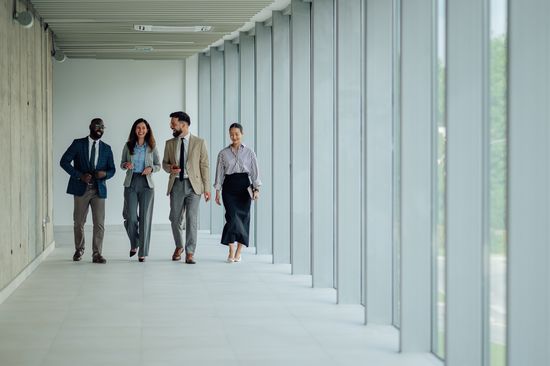 Several leaders of different backgrounds and genders walk down a hallway.