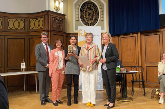Die Preisträgerinnen des erfolgreichen Projekts "MehrGrüneSchulen" mit Minister Polaschek und Ministerin Gewessler. Azra Korjenic hält die Trophäe.