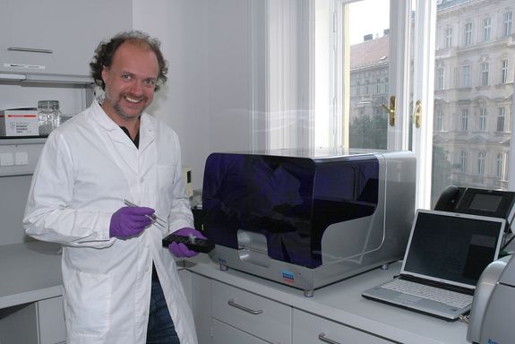 Prof. Andreas Farnleitner bei der Laborarbeit mit Proben in Pipetten und Pinzette in der Hand, neben ihm ein PCR-Gerät, dahinter ein Fenster.