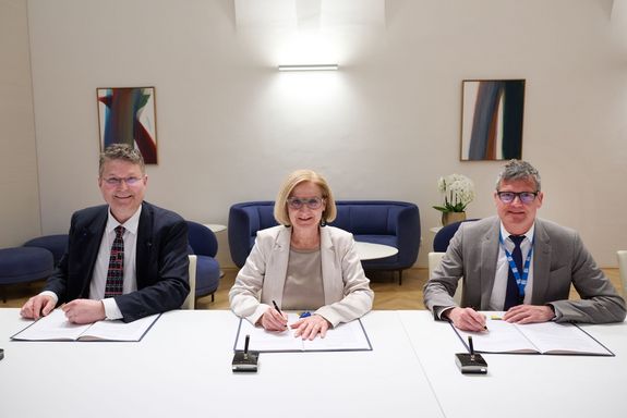 Franz Renz, Johanna Mikl-Leitner und Jens Schneider sitzen an einem Tisch, vor Ihnen jeweils eine Mappe in der sie gerade unterschreiben