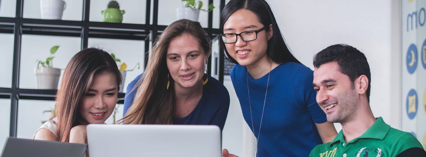 Studierende beraten sich vor einem Laptop