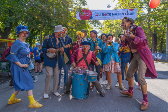 Eine Gruppe Clowns mit Instrumenten in der Prater Hauptallee.