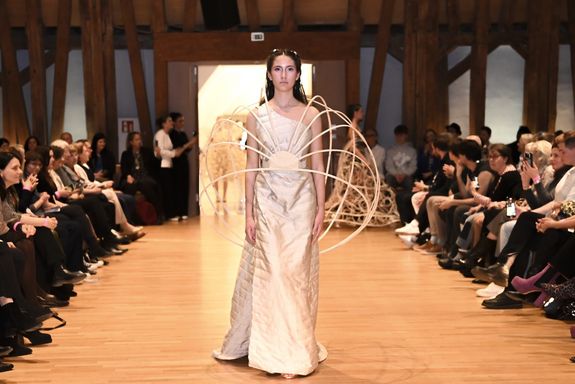 Model mit Kleid in weiß und Holzkonstruktion am Rücken