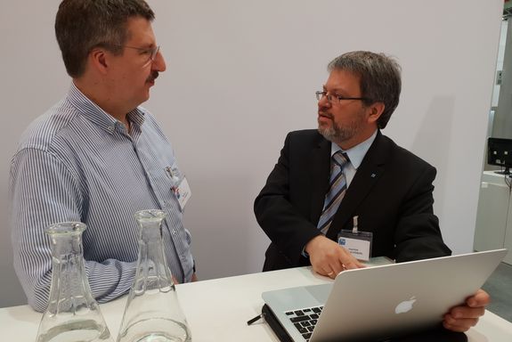 Prof. Dr. Michael Harasek (left) and Prof. Dr. Joachim Schöberl (right) talking in the meeting area of ​​the TU Wien stand.