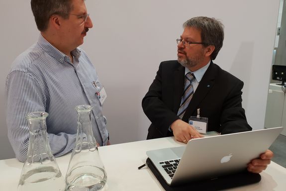 Prof. Dr. Michael Harasek (left) and Prof. Dr. Joachim Schöberl (right) talking in the meeting area of the TU Wien stand.