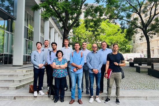 Einige Mitglieder des Projektteams, stehend vor Gebäude, Bäume und Parkbänke im Hintergrund.