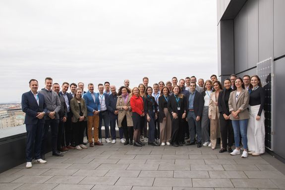 A group of people (executives from Porsche Holding and students of the Data-Driven Business MBA) are standing on the roof terrace of a building and smiling.