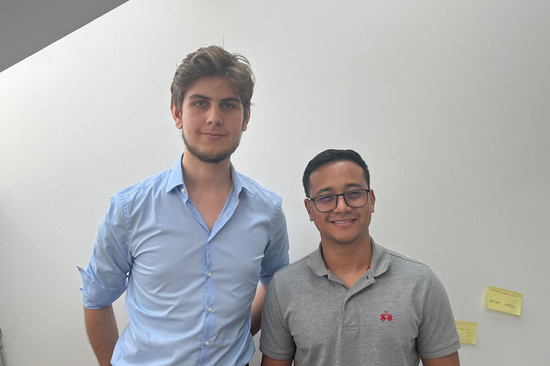 Foto der beiden genannten Personen, die nebeneinander vor einer weißen Wand stehen.