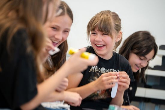 Kindergruppe lachend, Großaufnahme, in der Hand Bastelmaterial