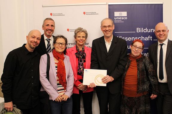 Gruppenfoto mit sieben Personen, eine davon hält eine Urkunde in Händen