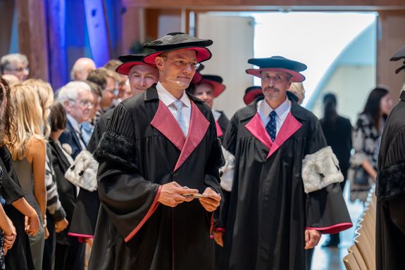 Der Moderator und das neue Rektorat in Festgewand ziehen in den Saal ein