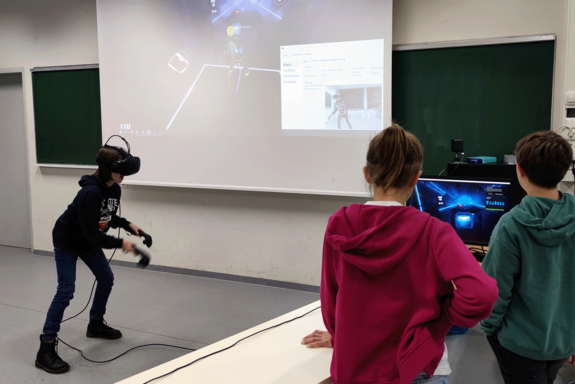 Kind mit VR-Brille vor Leinwand.