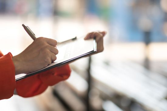 A woman is checking off a list on a clipboard.