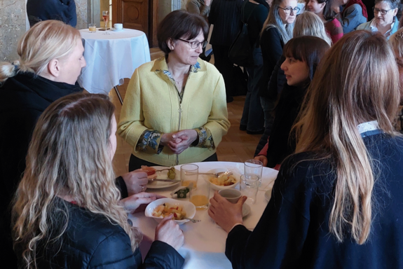 Vizerektorin Koch im Gespräch an einem Stehtisch mit Frauen. Sie trägt eine gelbe Jacke.