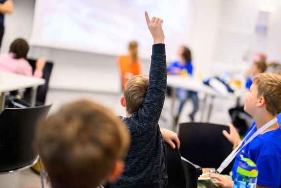 Kinder sitzend, einer zeigt auf