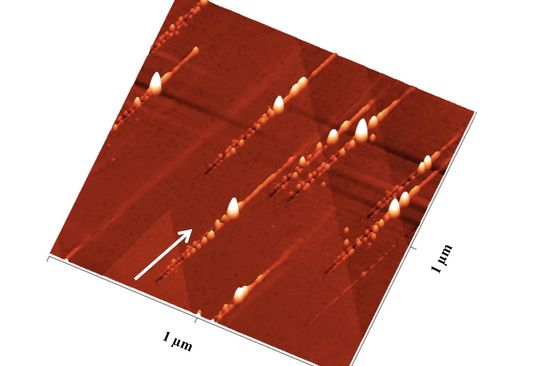 [Translate to English:] Nanostrukturen nach dem Ionenbeschuss: Der Pfeil zeigt die Richtung der Ionen an: Zunächst ensteht ein Graben mit Nanohillocks an beiden Seiten, ein besonders großer Hügel zeigt den Impakt-Punkt an, danach ist noch eine Erhebung entlang des Pfades zu sehen