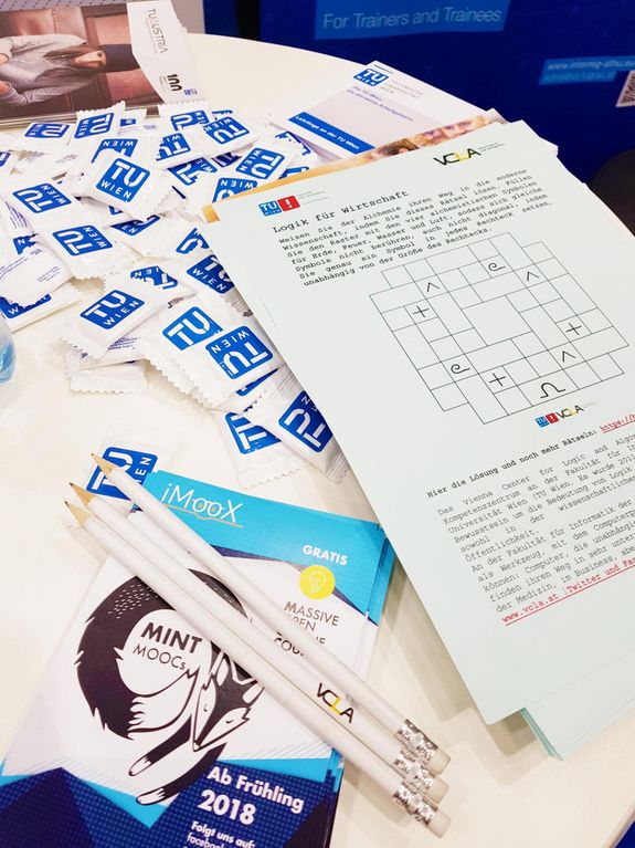 Infotresen mit TU-Traubenzucker, Logikspiel, MOOC-Flyer und Bleistifte