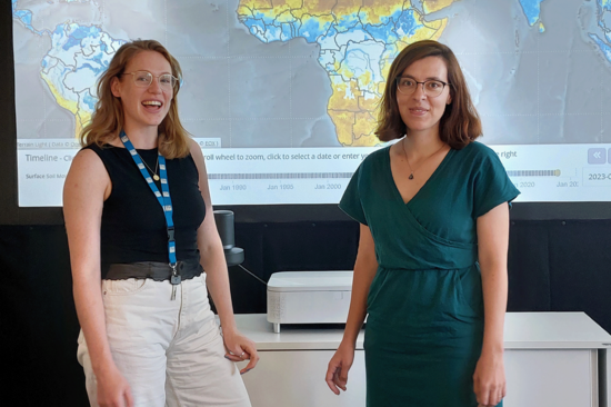 Johanna Lems und Ruxandra-Maria Zotta von der CLIMERS-Gruppe vor einem Screen mit einem von ihnen erstellten Klimabild. Beide lächeln.