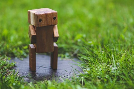 Kleiner Roboter aus Holz auf grüner Wiese