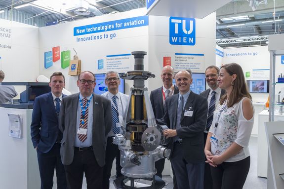 Visitors and exhibitors around a rotorcraft gearbox at the TU Wien stand