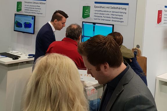 Zwei Aussteller (TU Wien) sprechen mit einigen Besuchern am TU Wien Stand