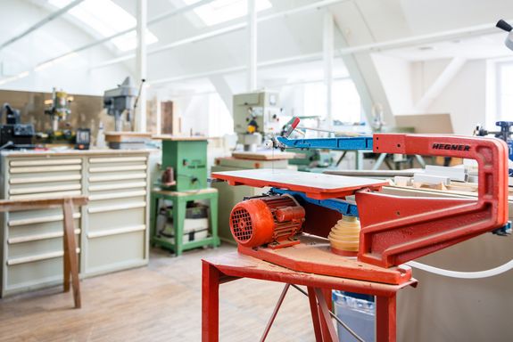Ein Werkstatt in dem viele unterschiedliche Maschinen für die Materialbearbeitung platziert sind. Der Raum ist sehr gut beleuchtet.