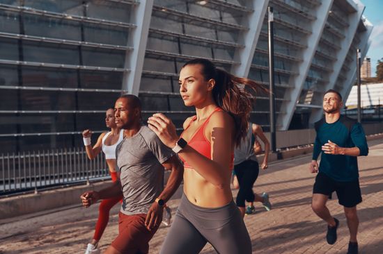 Several people of different genders and backgrounds jogging together
