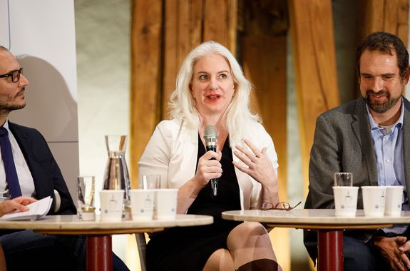 Großaufnahme von Julie Rosser, die ins Mikrofon spricht. Links ist Florian Rudroff zu sehen, rechts Philipp Thurner.