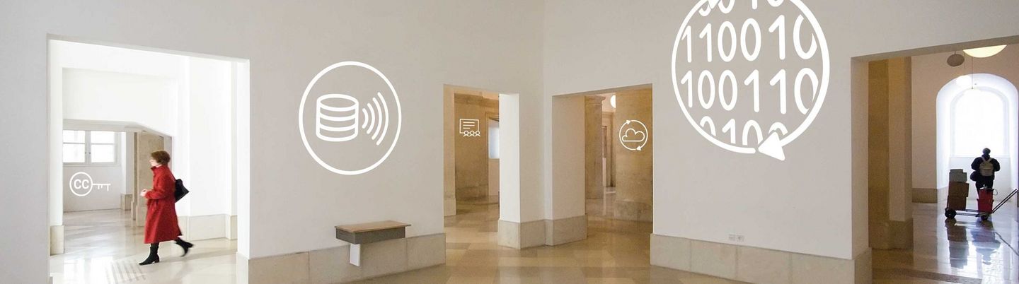 Das Bild zeigt ein Foto der Aula der TU Wien mit darübergelgten FDM-Symbolen.