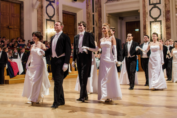Die Eröffnung des TU-Balls mit festlich gekleideten Paaren, die Damen tragen weiße Kleider, die Herren Smoking und weiße Hemden.