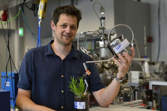 Alexander Opitz im Labor, mit Gieskanne und Planze