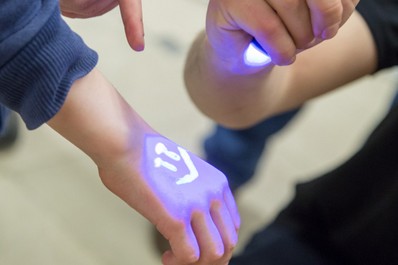 Eine Hand von einem Kind mit der Ultraviolettstrahlung