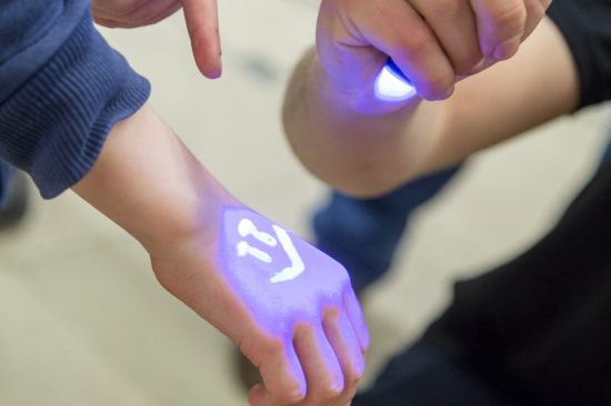 Eine Hand von einem Kind mit der Ultraviolettstrahlung