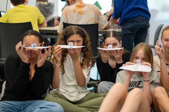 Kinder sitzend mit Kompass aus Papier in der Hand