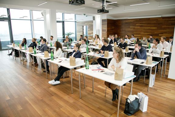 Studierende sitzend bei Tischen